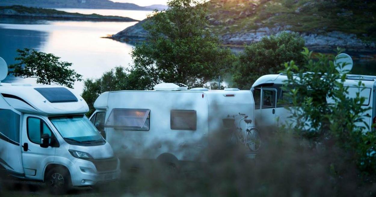 Campervans parked by the lake with a sunset