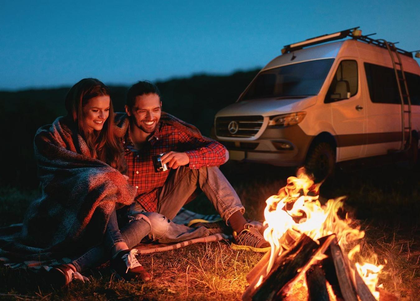 A couple sitting at a campfire outside of a Tiffin RV