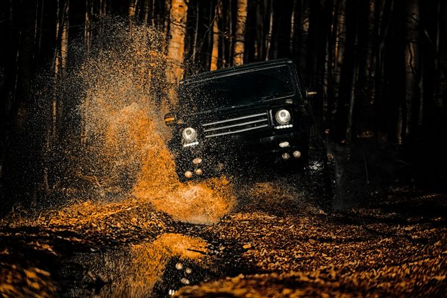 SUV off-roads through mud in a forest