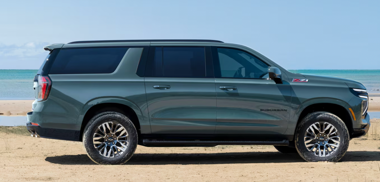 A green Chevrolet Suburban parked on the beach