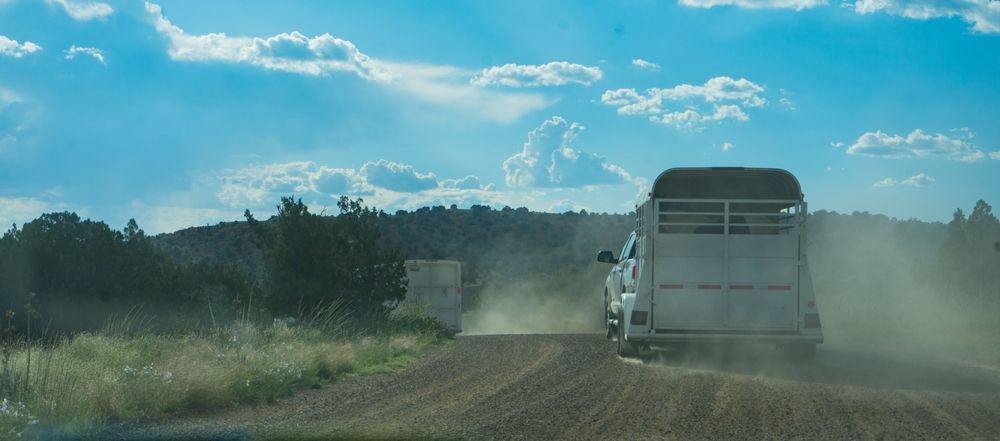 Horse trailer behind a truck on a dusty road