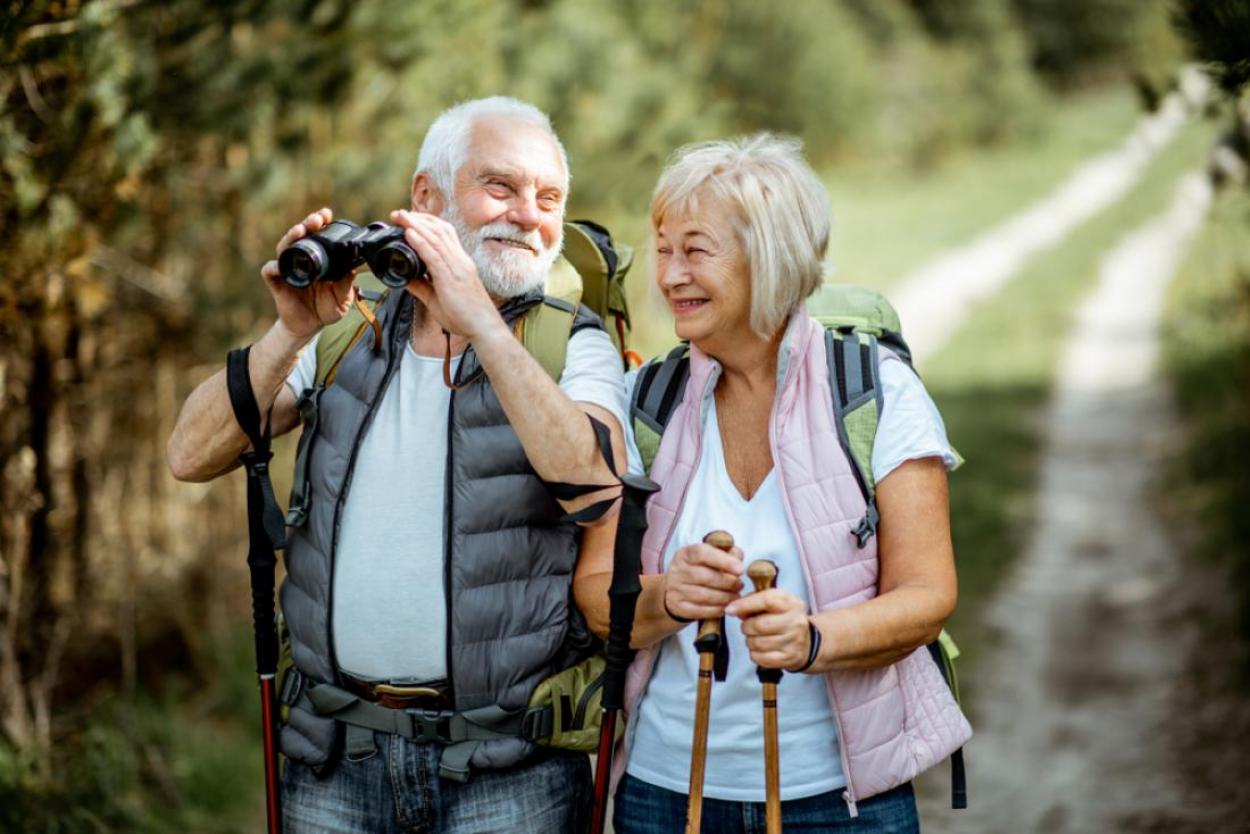 Mature, happy couple using binoculars on a hike