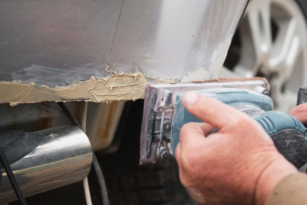 Close up of a sanding tool next to a car