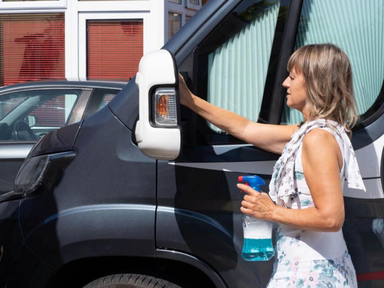 Woman cleaning side mirror an RV