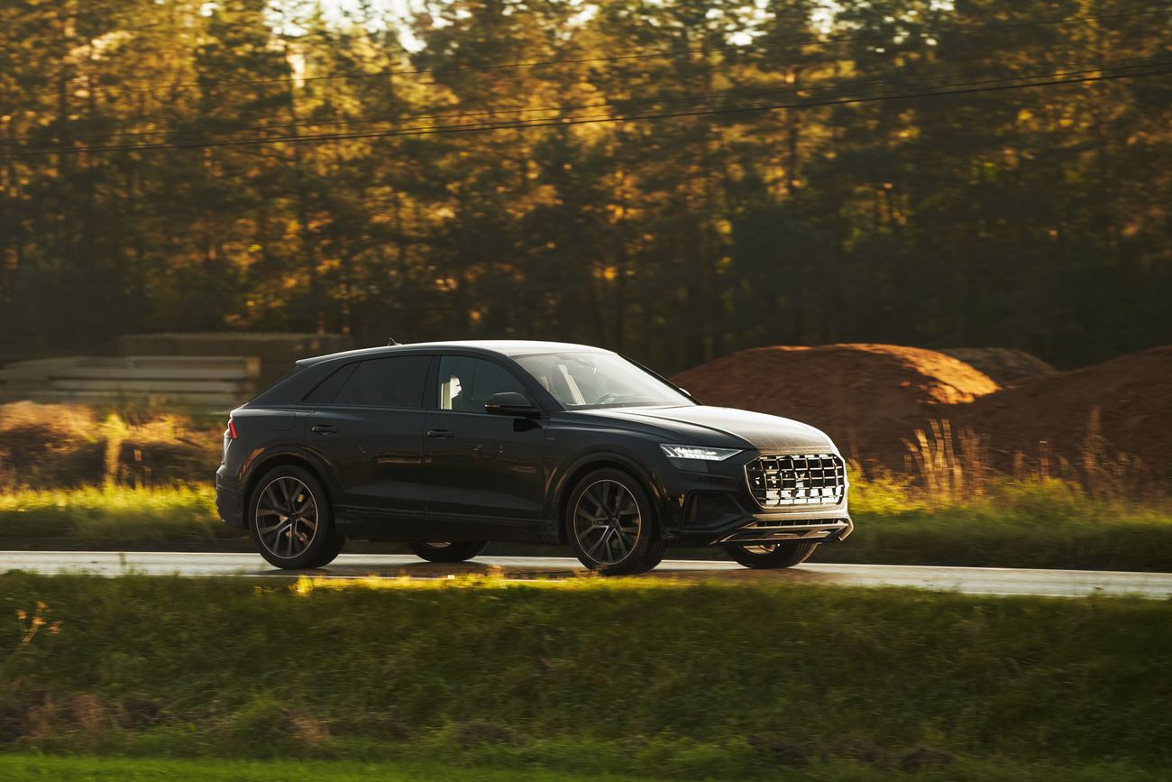 A black SUV drives past trees
