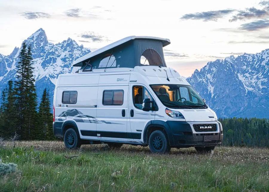 2023 White Winnebago Solis, National Parks Foundation Edition, parked in front of the Rocky Mountains with its pop top lifted