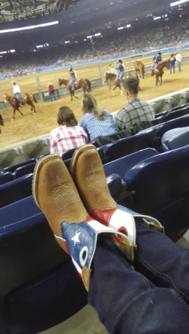Cowboy boots resting on the back of stadium seats at a stock show