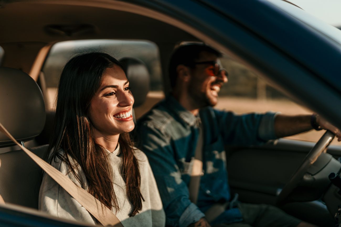 A smiling man and woman sit in a car