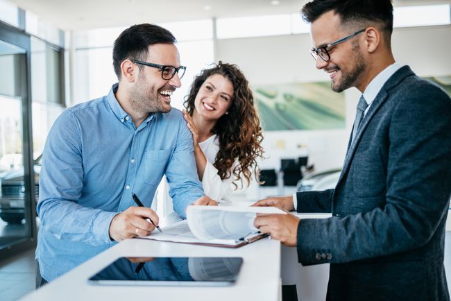Couple and a salesperson in a car dealership
