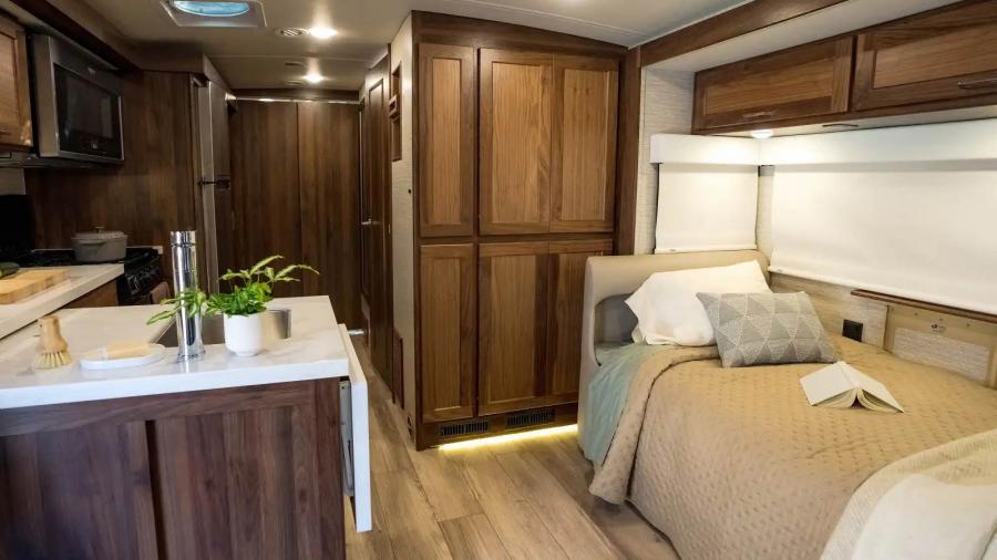 Living and dining room space inside a large RV with a plant and decor on the counter