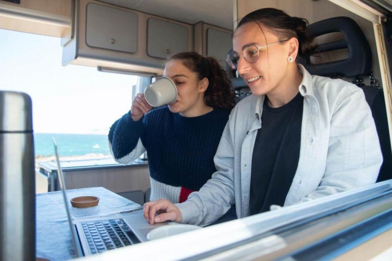 Two women on a laptop inside a campervan
