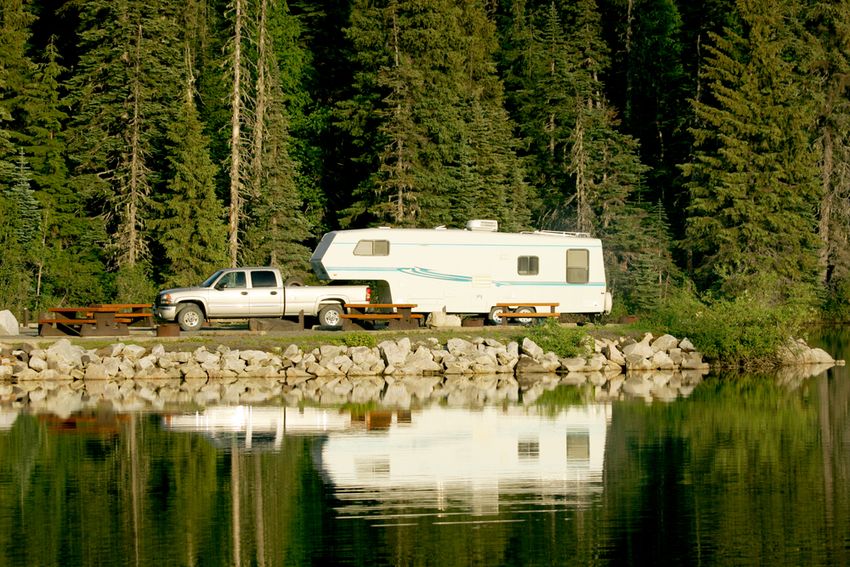 Fifth wheel camper and truck next to a lake