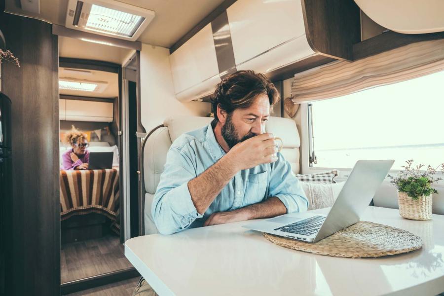 Couple working in two different spots inside an RV each on their own laptop