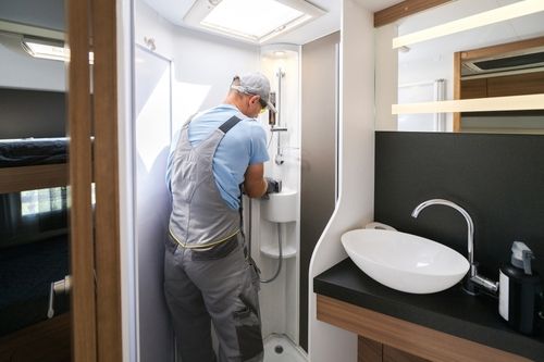 Professional RV plumber works in an RV bathroom