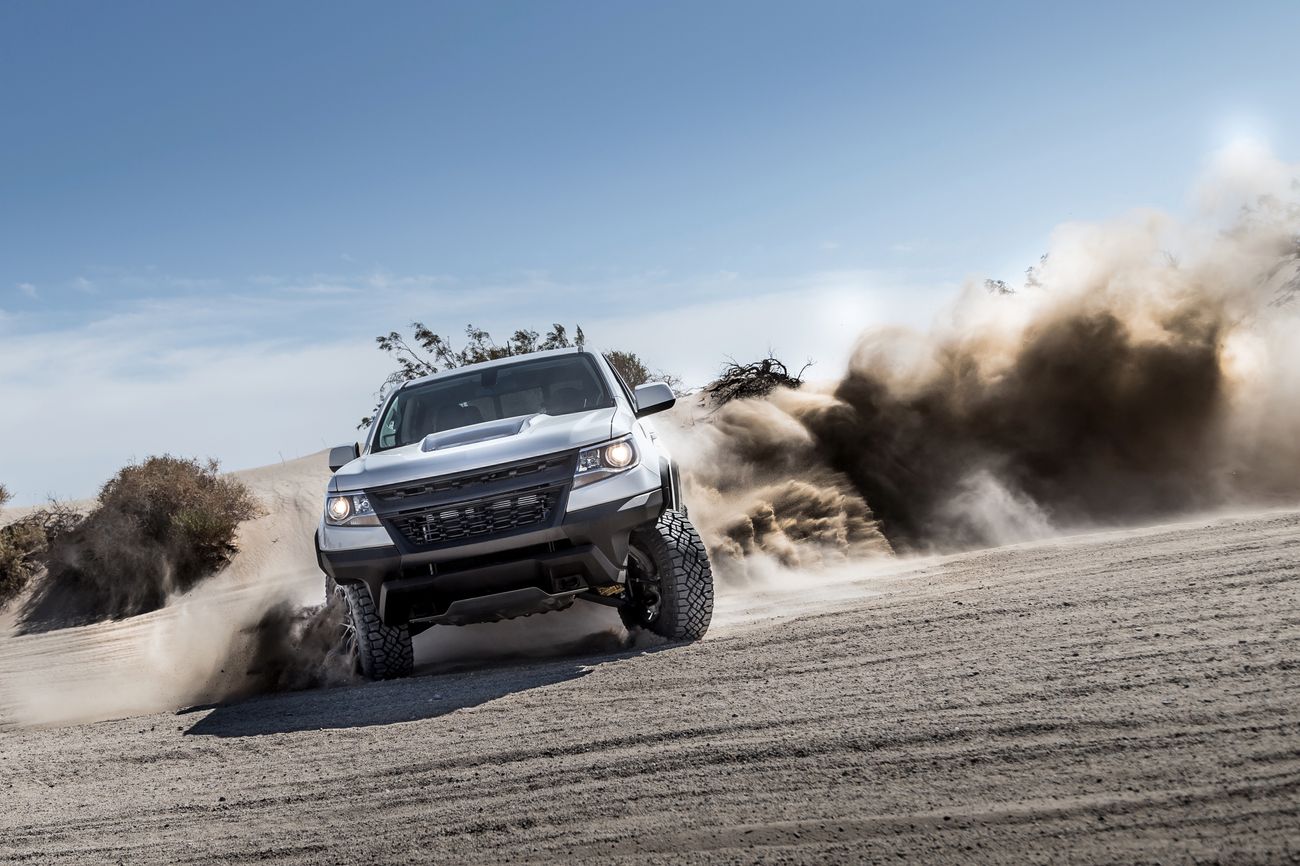 A white truck drives through sand