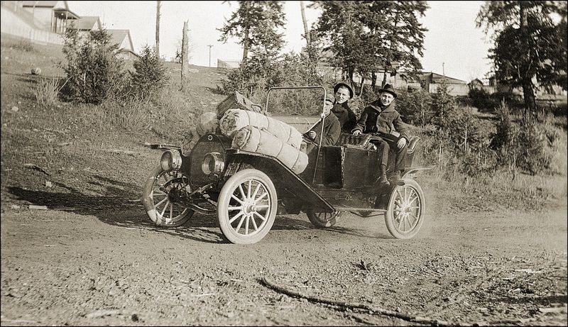 Man and woman drive a car with tent rolls in the early 20th century