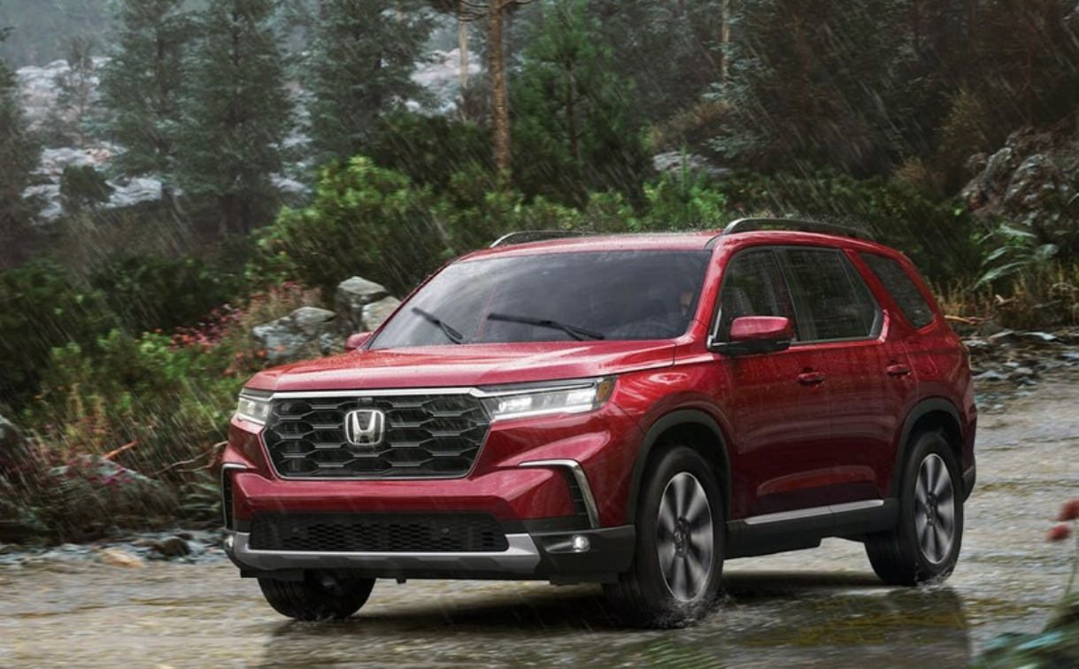 A red Honda Pilot drives in the rain