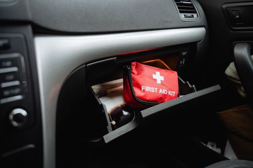 A red first aid kit bag in the glove compartment of a car