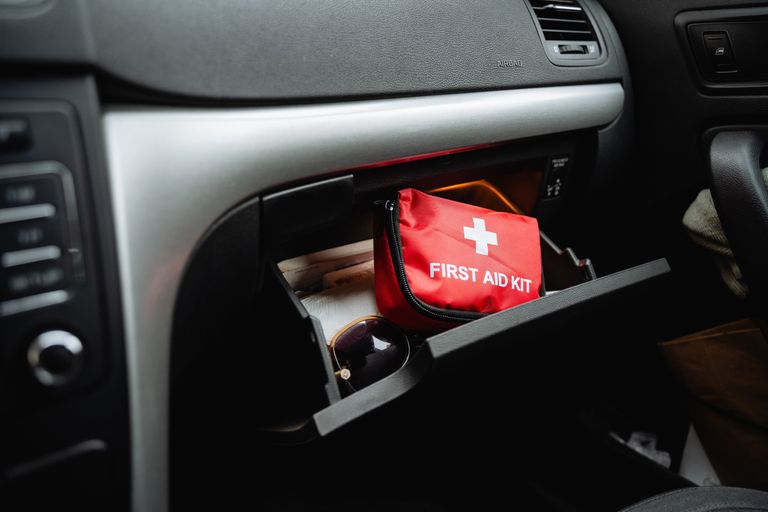 A red first aid kit bag in the glove compartment of a car