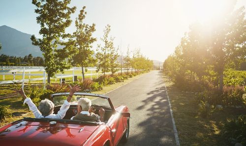 A couple rides in a convertible in a rural setting