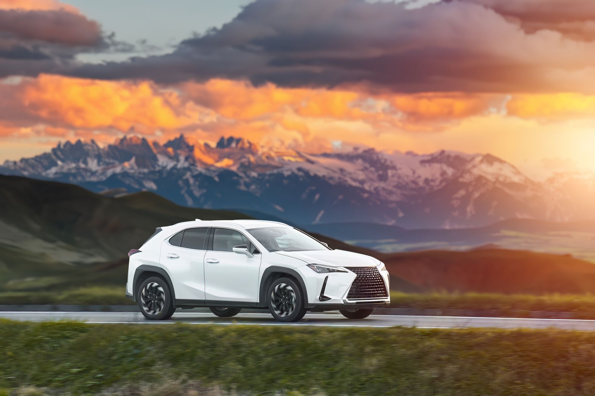 A white SUV drives in front of mountains