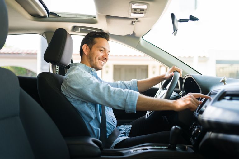 A man reaches toward his car's infotainment system