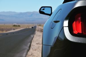 A view of a dark car's rearview mirror with a mountain range in the distance