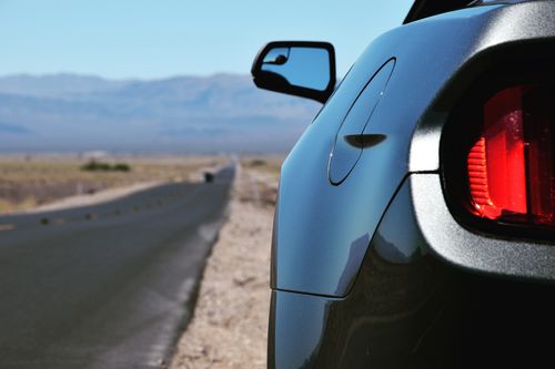 A view of a dark car's rearview mirror with a mountain range in the distance