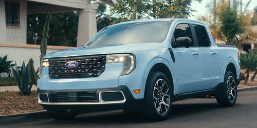 A light blue Ford Maverick parked near cacti and palm trees