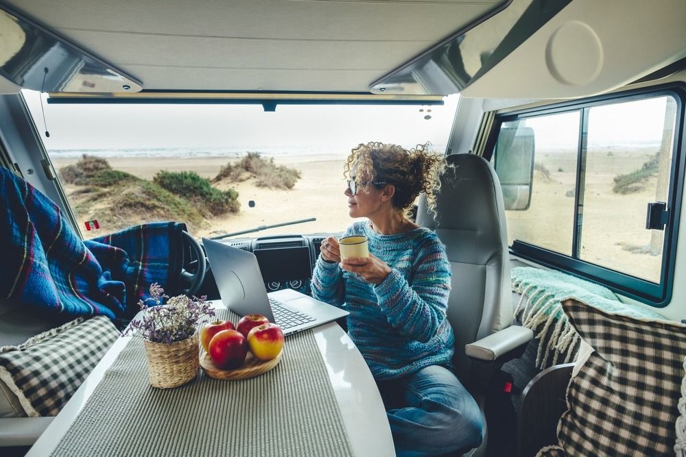 Woman sitting with computer and mug inside an RV
