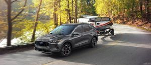 Gray Ford Escape tows a boat around a tight curve