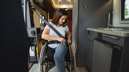 Woman in a wheelchair buckles into an RV