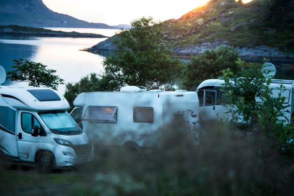 Campervans parked by the lake with a sunset