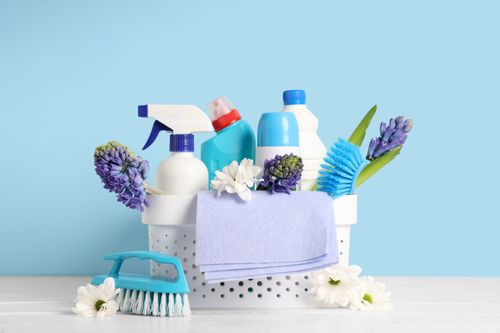 A basket of cleaning supplies in front of a blue wall
