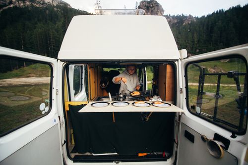 Person cooking in the back of a campervan