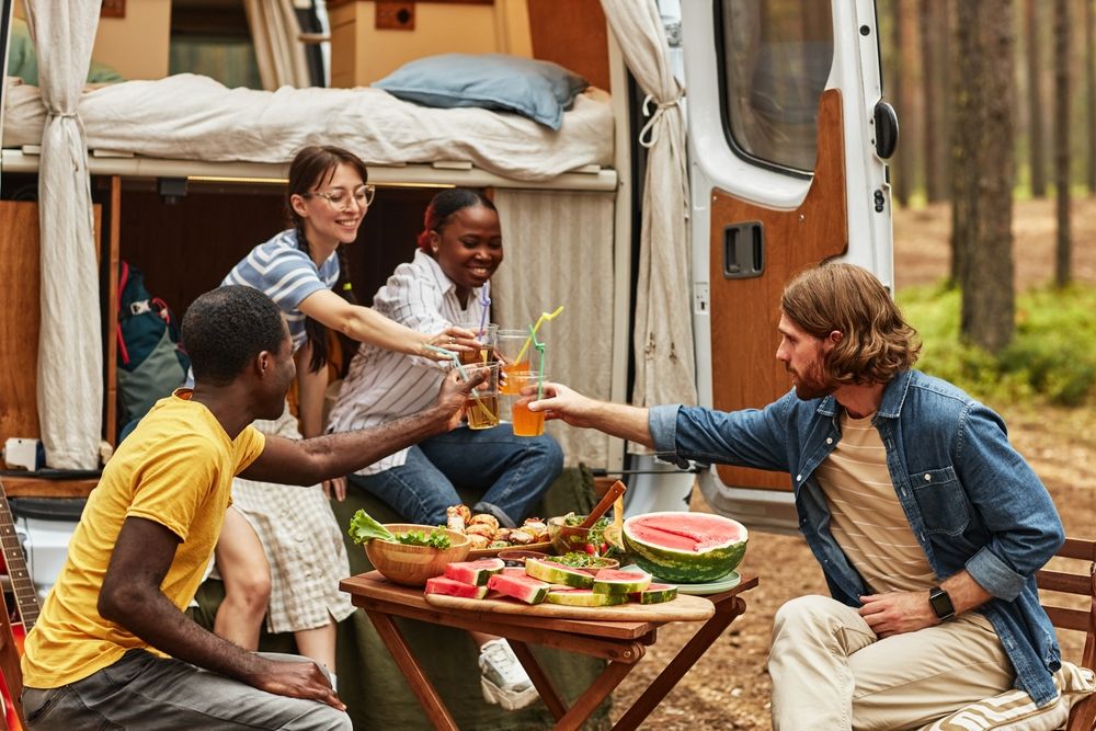 Group of people gathered around a small table in front of an RV
