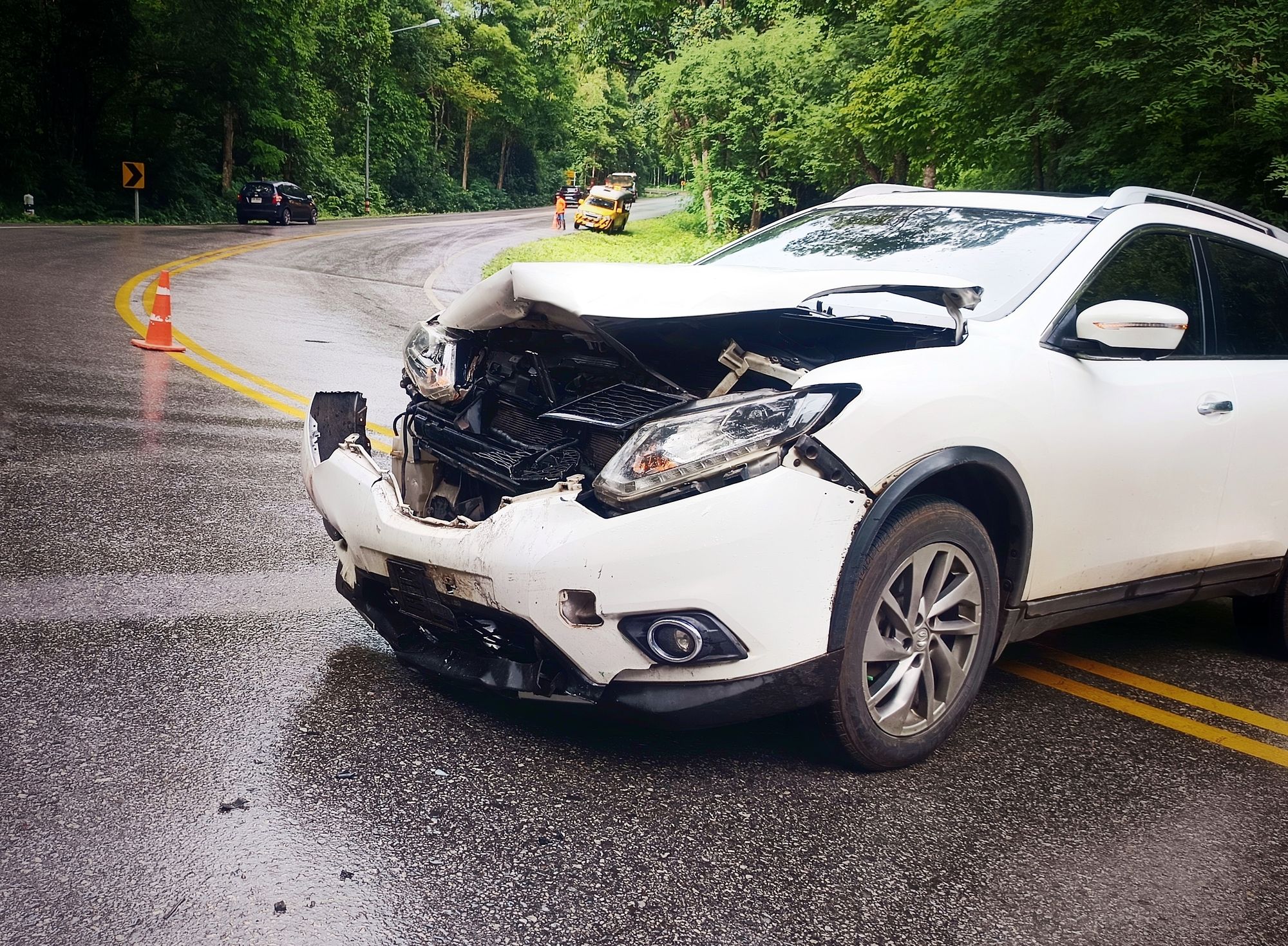 A severely damaged white SUV sits in the road