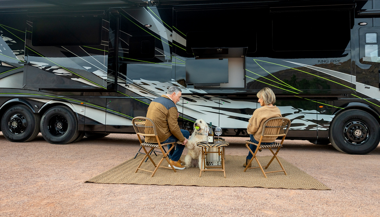 Couple sitting outside of a large RV