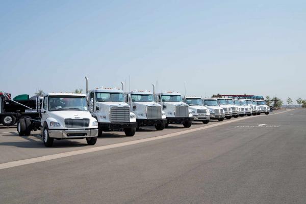 Line of commercial trucks parked under a blue sky