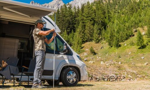 Man extends pole outside a parked RV