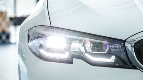 A close-in shot of a light colored car's shining headlights