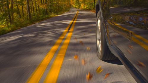 A car drives on a road with leaves on it