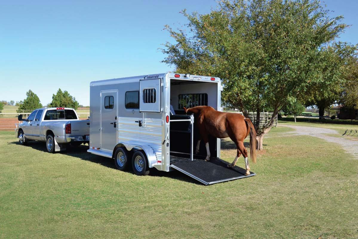 Horse being loaded into a trailer pulled by a pickup truck