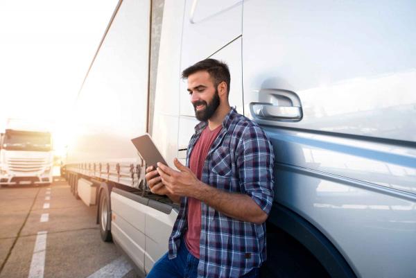 Man on a tablet outside of a commercial truck with trailer