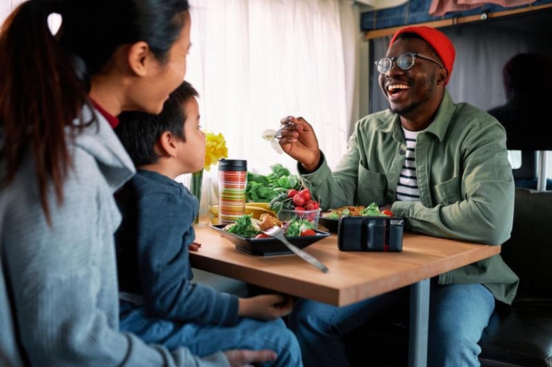 Family enjoys dinner together inside an RV