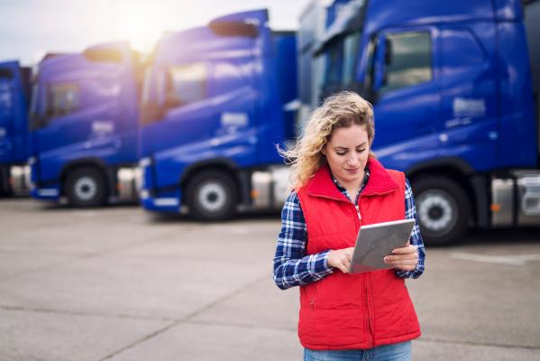 Woman in front of a fleet of semi trucks looking at an ipad