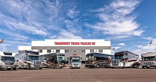 Five RVs parked in front of the Transwest Truck Trailer RV of Frederick building with a blue sky above