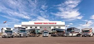 Five RVs parked in front of the Transwest Truck Trailer RV of Frederick building with a blue sky above