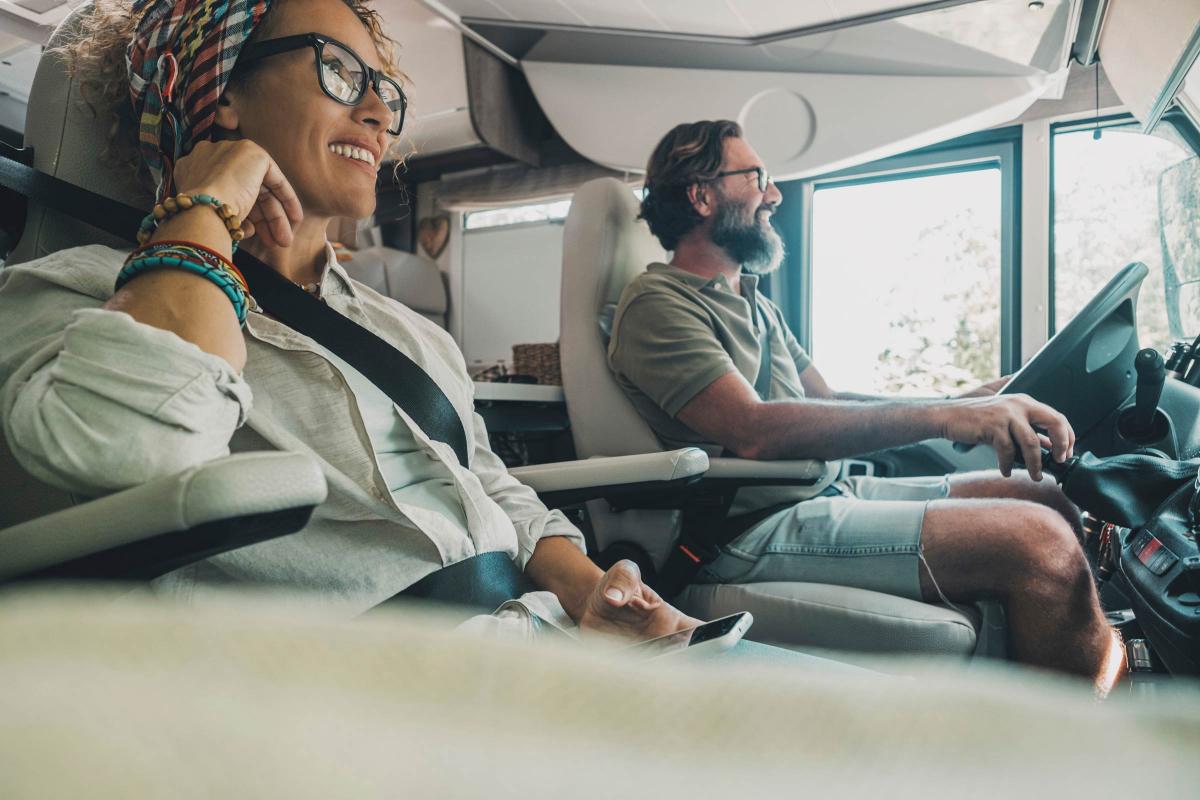 Couple sitting inside an RV while driving. Both look happy