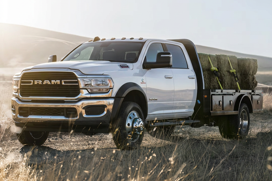 Front three-quarter view of the 2026 RAM 5500 Tradesman driving on a rugged dirt road at a job site